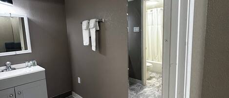 Une salle de bain avec un sol en marbre, un lavabo blanc et un grand miroir.