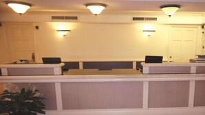 A reception area with a reception desk, two computer stations, and a potted plant.
