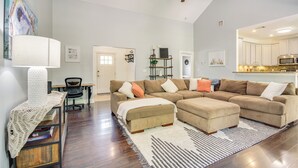 Uma sala de estar moderna com um sofá modular, uma mesa de centro e um espaço de jantar com mesa e cadeiras.