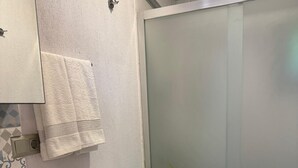 Een badkamer met een wit wastafel, donkerhouten kastjes, een wit toilet en een douchecabine van glas.