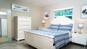 A bedroom with a bed, nightstands, a dresser, a mirror, and artwork on the walls. - Delray Ocean Breeze (Delray Beach)
