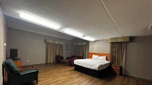 Ein Hotelzimmer mit einem Bett, zwei Sesseln, einem Schreibtisch und einem Fernseher.