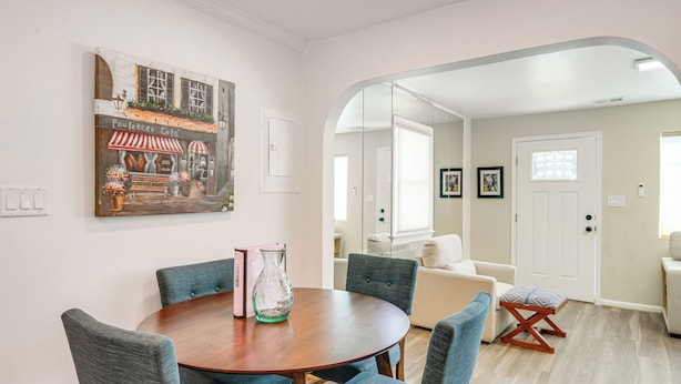 A dining area with a round table, blue upholstered chairs, and a painting of a cafe. - 2 Mi to Potomac Mills: Modern Home in Woodbridge (Woodbridge)