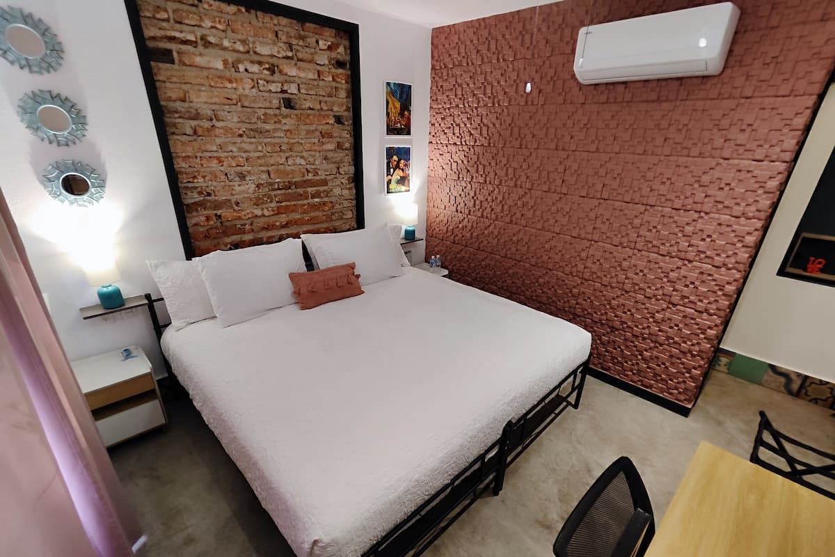 A bed with white bedding, a brick-patterned wall, a small table, and a chair.