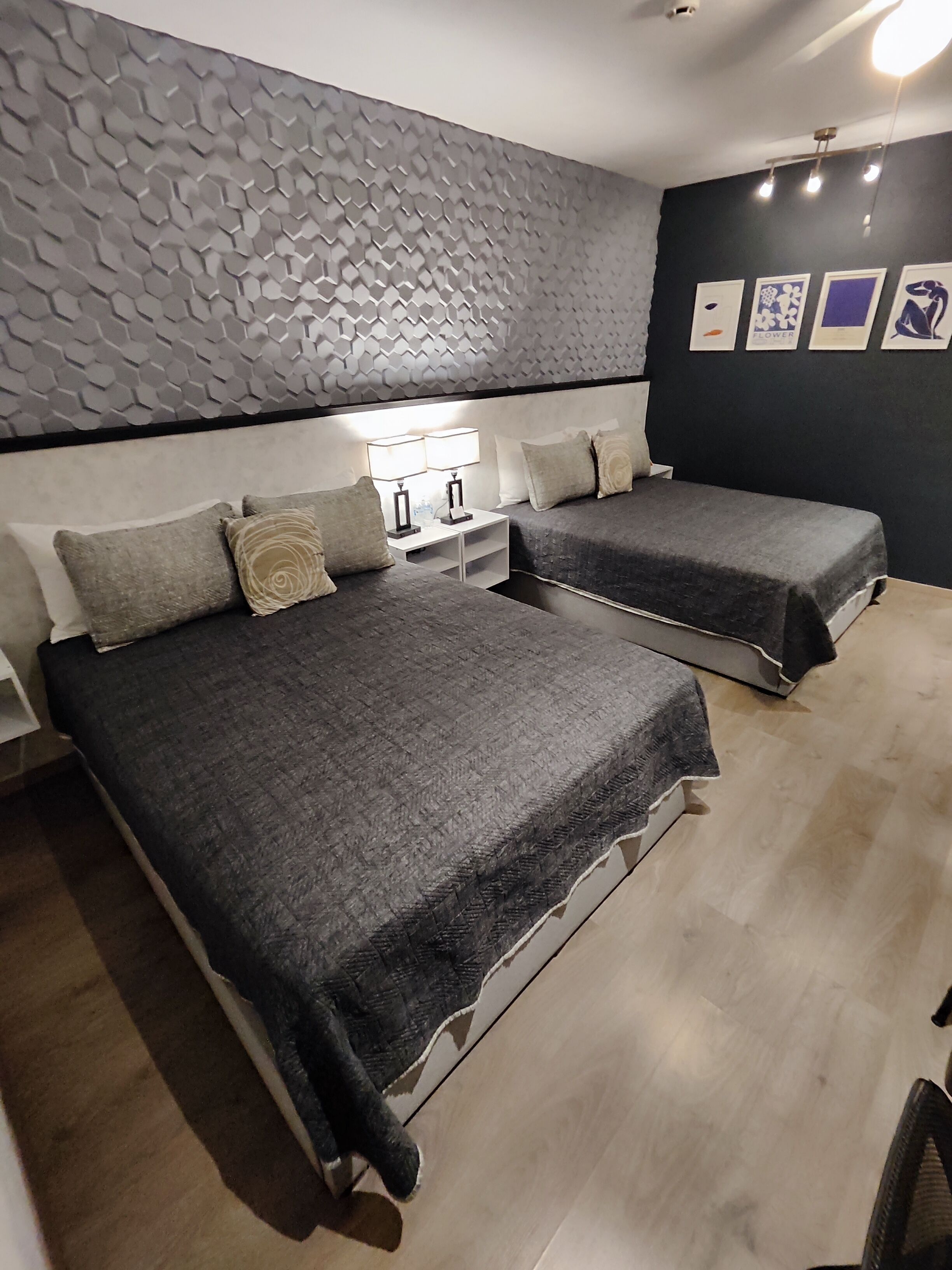 Habitación de hotel con dos camas, diseño moderno en la pared y una obra de arte.