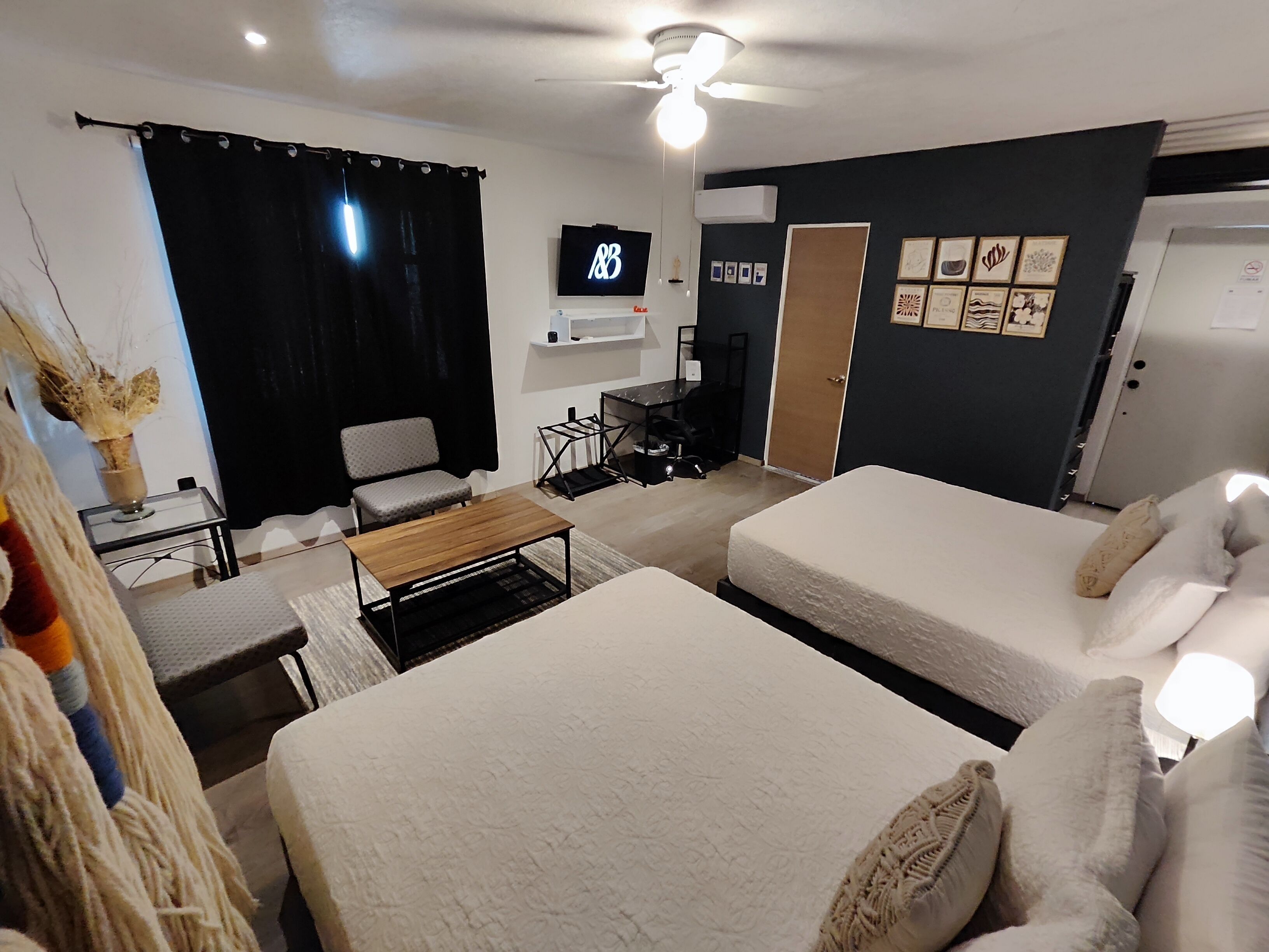 Une chambre d’hôtel avec deux lits, un bureau, une chaise, une télévision et une porte.