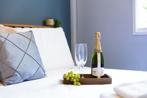 A bed with a pillow, a tray with a bottle of champagne, two glasses, and a bunch of grapes. - Apt piscina e AC com academia e vaga (São Paulo)