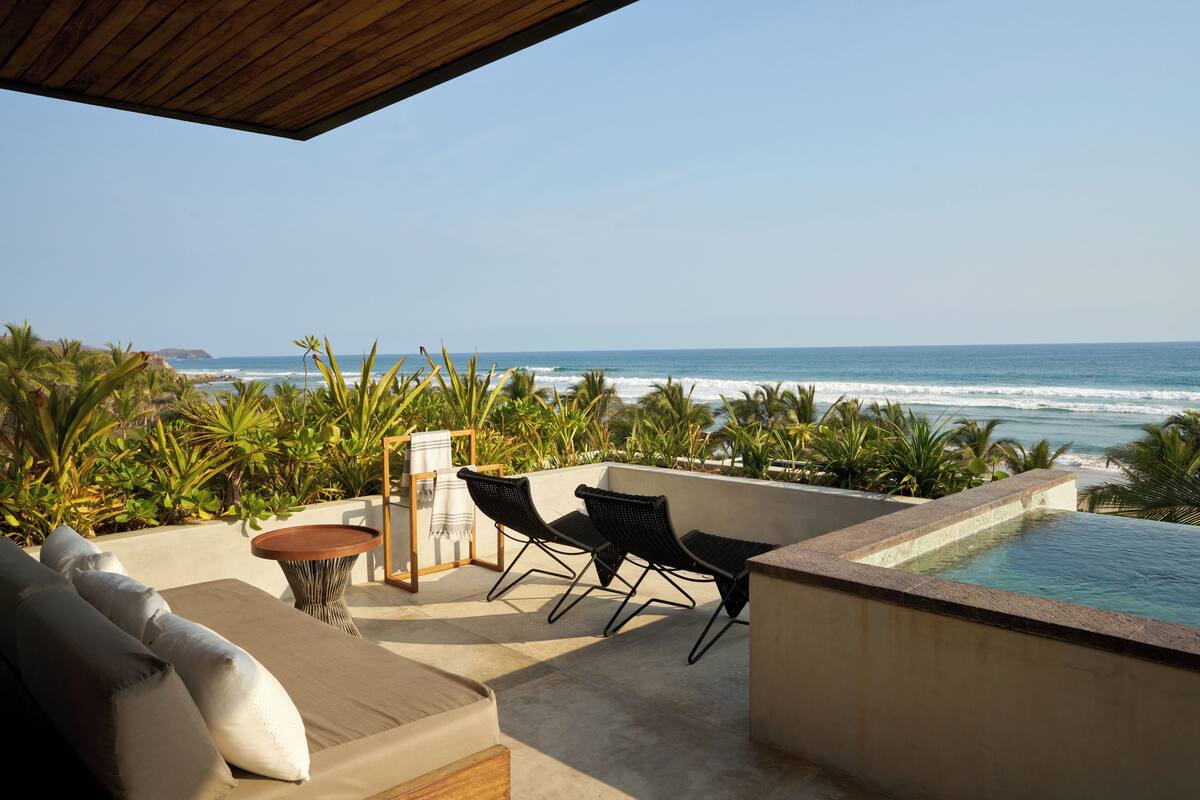 A rooftop terrace with a pool, seating area, and ocean view.