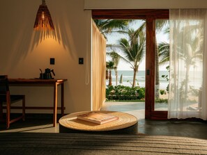 Une pièce avec vue sur l’océan, une table ronde en osier et un luminaire suspendu.
