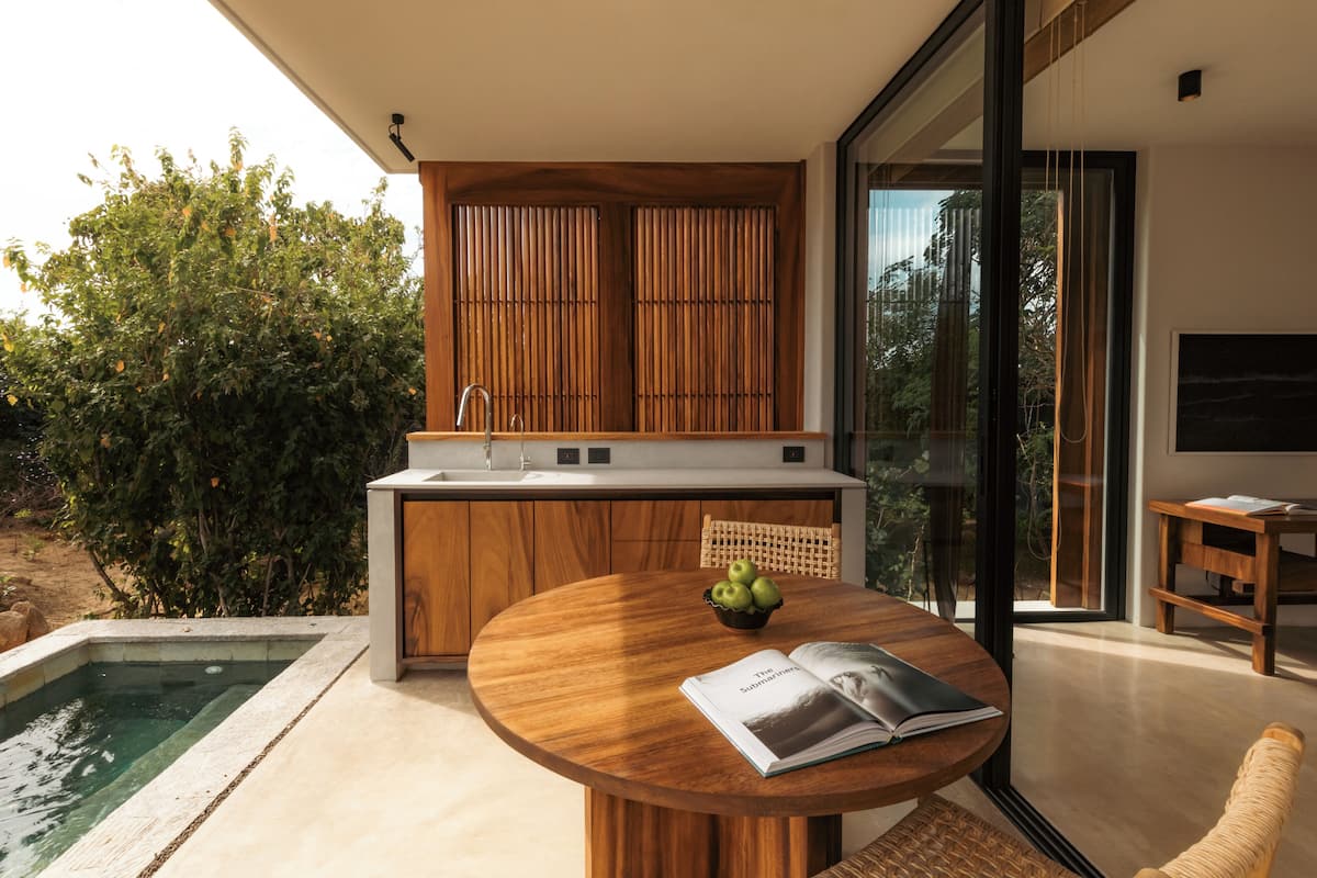 A modern kitchen with a wooden countertop, a built-in sink, and a dining area with a round table and a book.