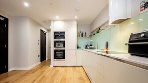 A modern kitchen with white cabinets, a built-in oven, and a NINA brand grill.