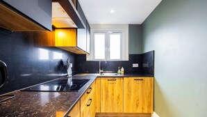 Una cucina moderna con un piano di lavoro nero, mobili in legno, un piano cottura integrato e una finestra sopra il lavello.