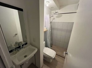 Bathroom features a sink, toilet, and shower area with a glass door.