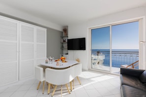 Un salon moderne comprenant un coin repas, un téléviseur à écran plat et un balcon avec vue sur la mer.