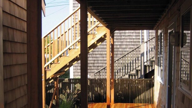 Una terraza de madera con una escalera que lleva a un espacio cubierto.