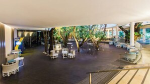 An indoor atrium with a seating area, trees, and a staircase. - The Pearl of Mactan (Lapu-Lapu City)
