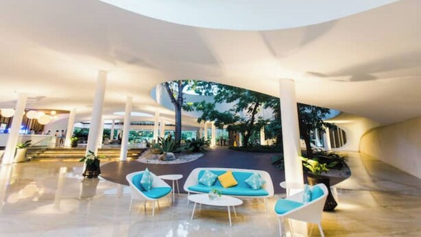 A spacious lobby with modern seating, a central garden area, and a curved ceiling design. - The Pearl of Mactan (Lapu-Lapu City)