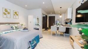 A modern bedroom with a large bed, a desk, and a dining area. - The Pearl of Mactan (Lapu-Lapu City)