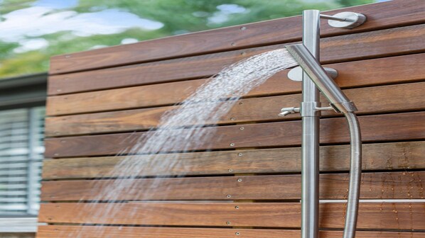 A showerhead mounted on a wooden wall with horizontal planks.