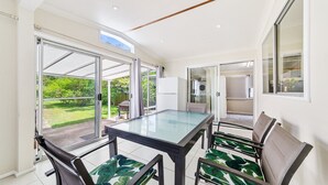 Una cocina moderna con una mesa de comedor de vidrio, sillas y vistas al jardín.