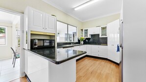 Una cocina moderna con armarios blancos, encimera negra y suelo de madera.