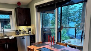 Une cuisine moderne avec des meubles en bois foncé, un lave-vaisselle en acier inoxydable et une fenêtre donnant sur un balcon.