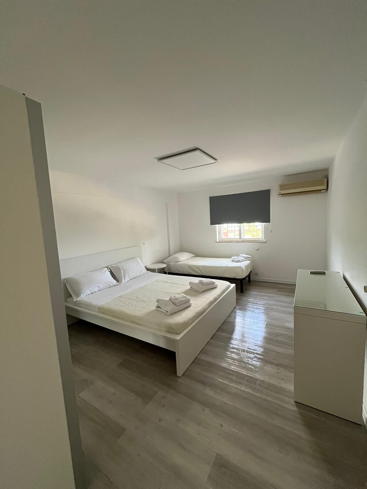 Un dormitorio con una cama grande, una cama más pequeña, un escritorio y una ventana.