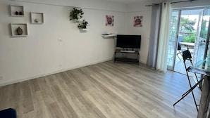 A spacious living room with a flat-screen TV, wooden flooring, and a sliding glass door leading to an outdoor area. - Porta Addaura (Palermo)