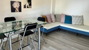 A modern living room with a glass dining table, black chairs, a blue sofa with patterned cushions, and two wall art pieces. - Porta Addaura (Palermo)