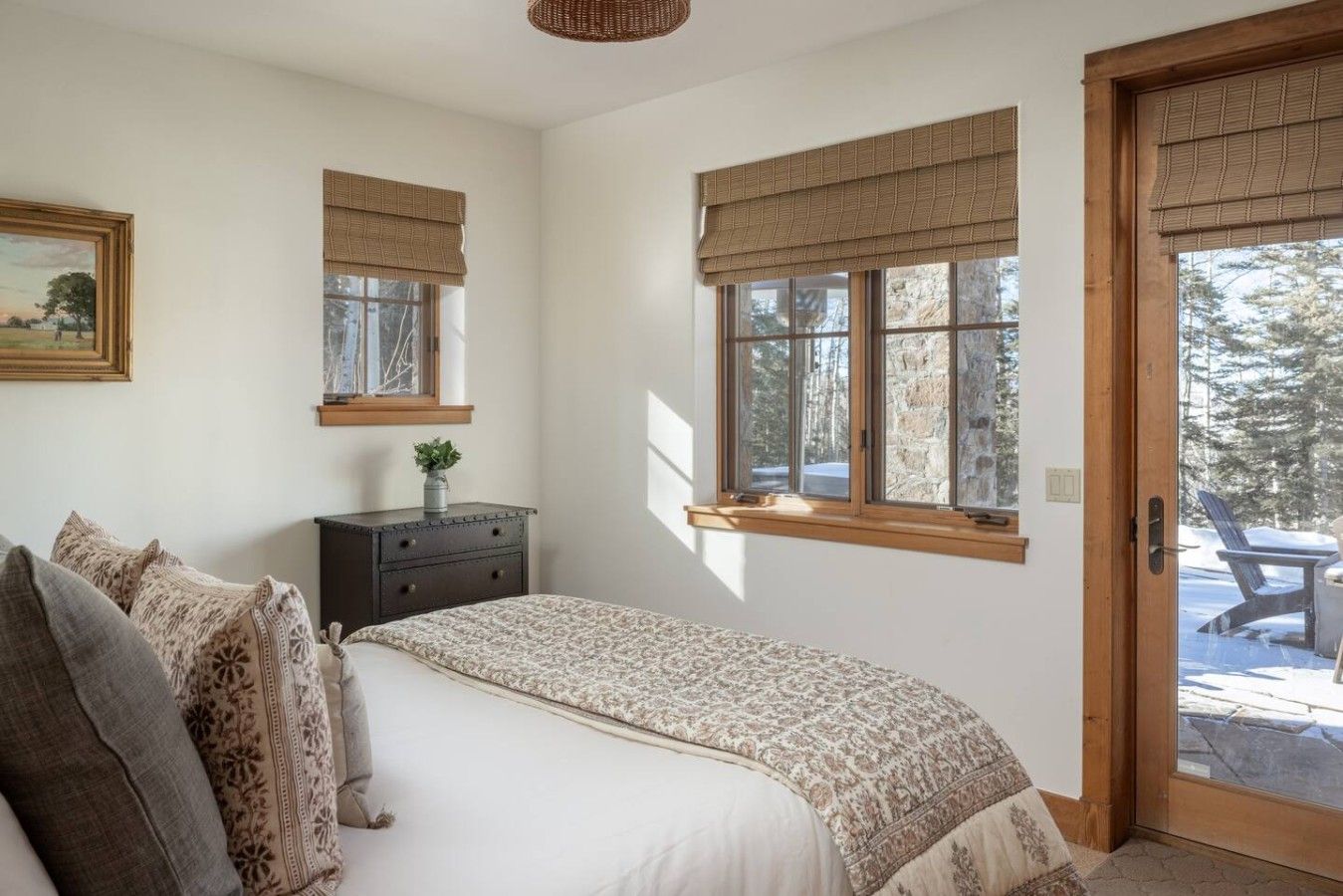 Een slaapkamer met een bed, een dressoir en ramen voorzien van zonwering.