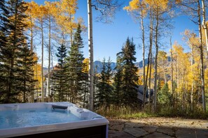 A hot tub in a forested area with a mountain backdrop.