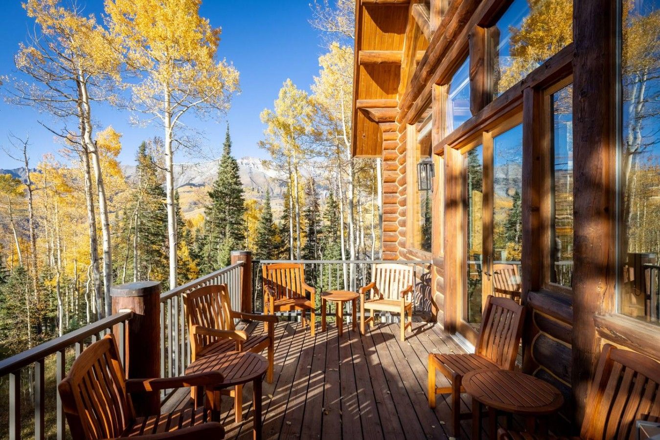 A wooden deck with outdoor furniture, overlooking a forested area.