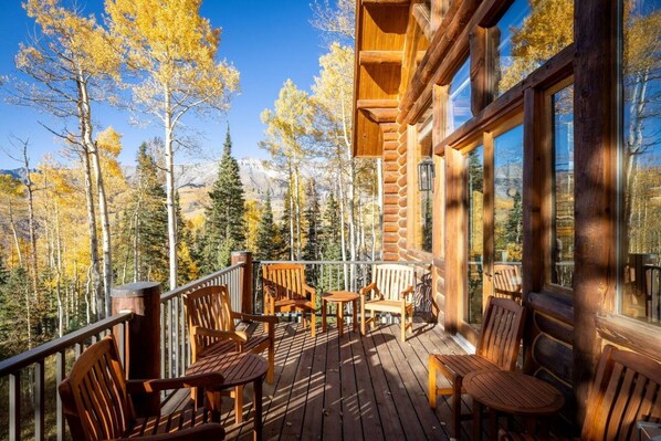A wooden deck with outdoor furniture, overlooking a forested area.