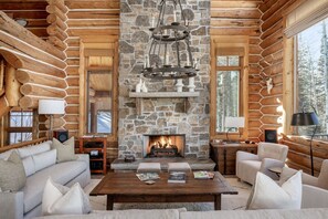 A log cabin interior with a stone fireplace, wooden furniture, and a cozy seating area.