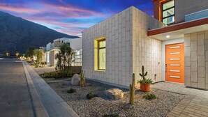 Una casa moderna con techo plano, un ventanal grande y una puerta con manijas horizontales.