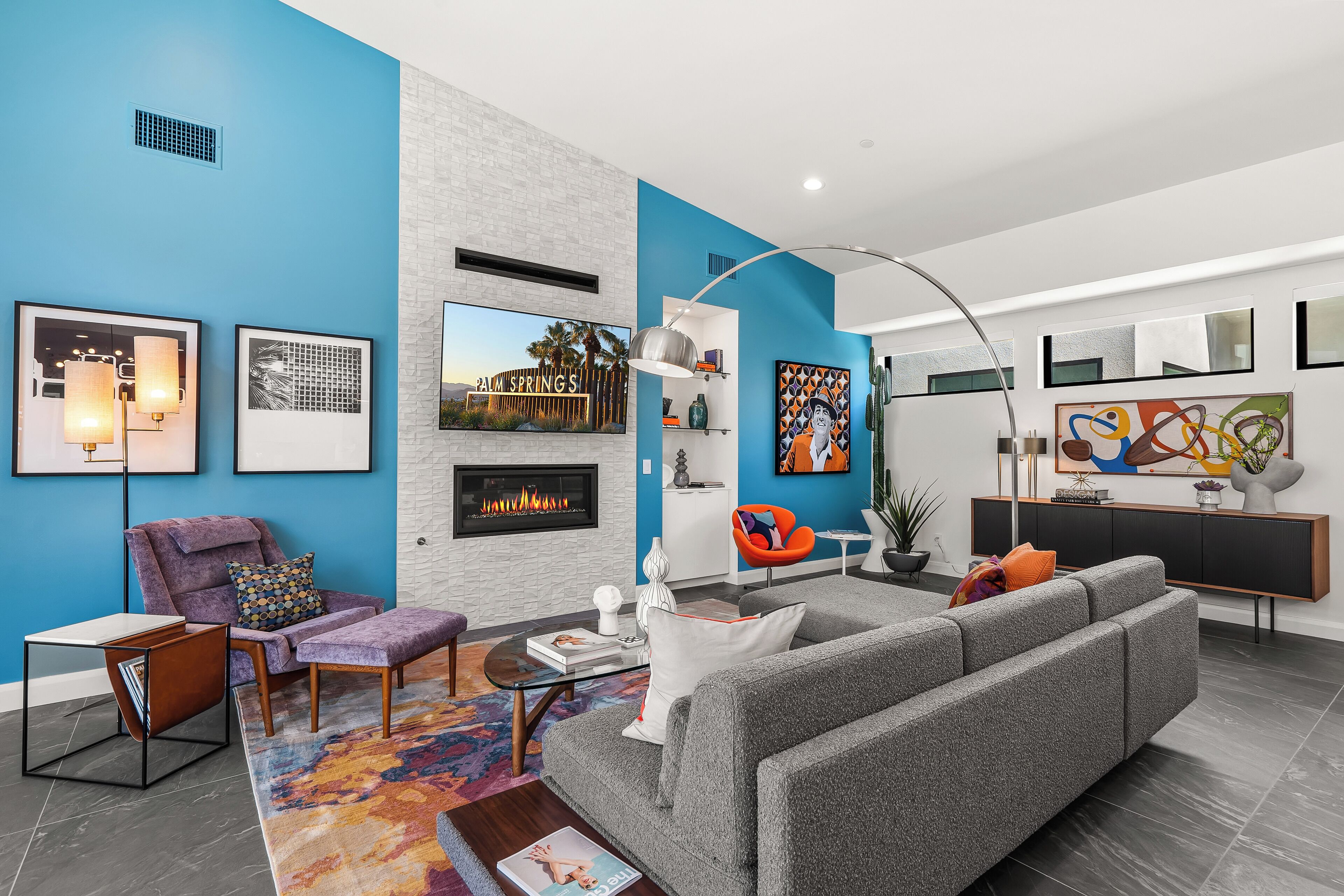 A modern living room with a grey sofa, a purple armchair, and a fireplace.