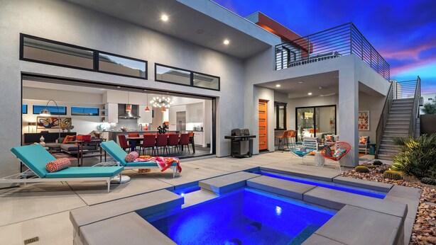 Una casa moderna con piscina, mobiliario de exterior y una escalera que conduce a un nivel superior.