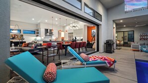 Un espacio moderno para vivir con piscina, sillones de descanso y comedor.