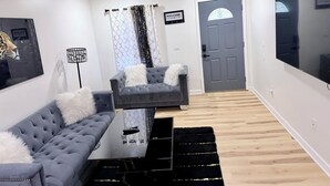 A modern living room with a sofa, a coffee table, a TV, and a door. - Your Home: Three bedrooms, accommodating 6 guests. (Columbus)