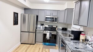 A modern kitchen with grey cabinets, stainless steel appliances, and a granite countertop. - Your Home: Three bedrooms, accommodating 6 guests. (Columbus)