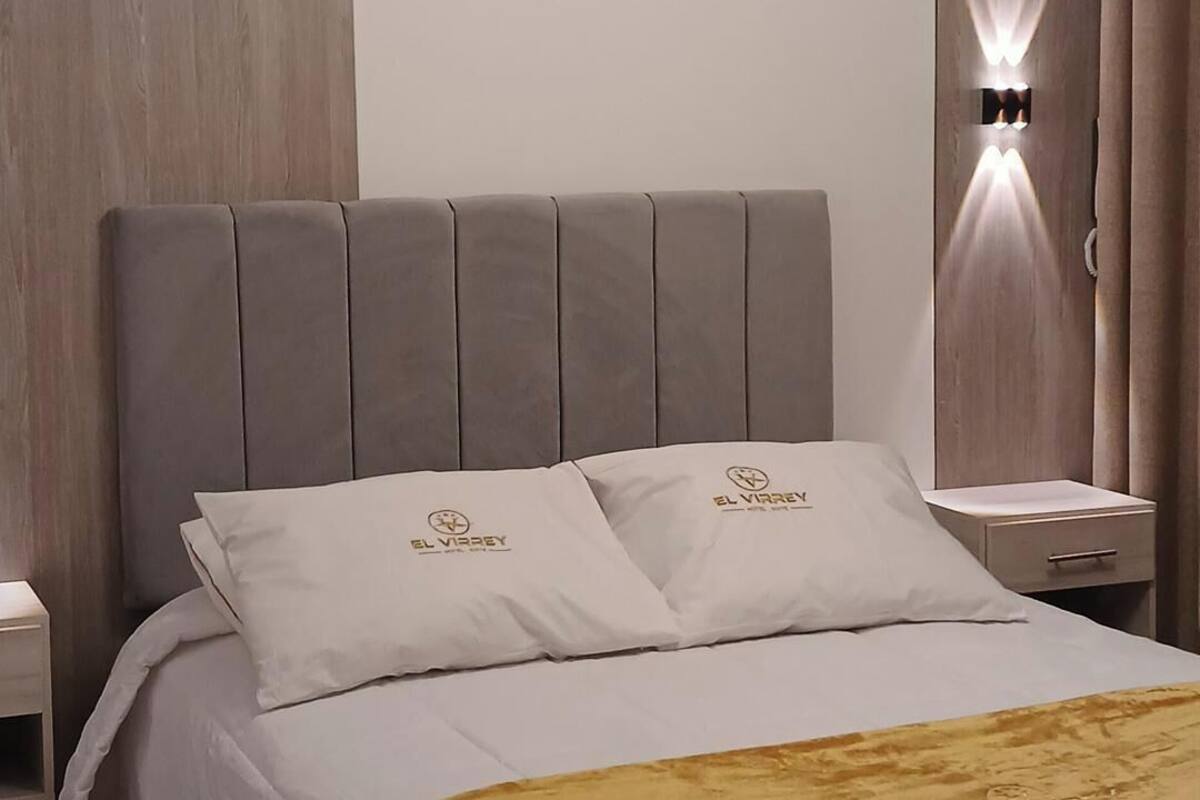 A modern bedroom with a large bed, a headboard, and a bedside table.