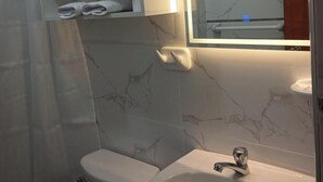 Et badeværelse med toilet, vask og et håndklædetørrestativ med foldede håndklæder.