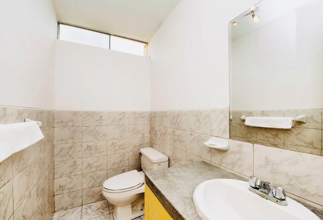 Un baño con inodoro, lavabo y espejo.
