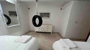 Una habitación pequeña y limpia con dos camas, un aparador y un espejo.
