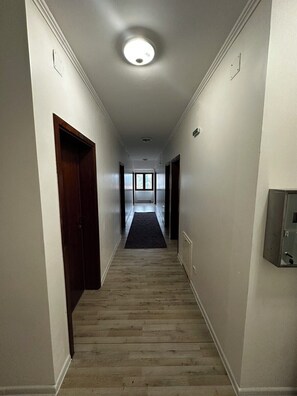 A narrow hallway with wooden flooring, white walls, and a ceiling light. - Hotel Citadela (Sarajevo)