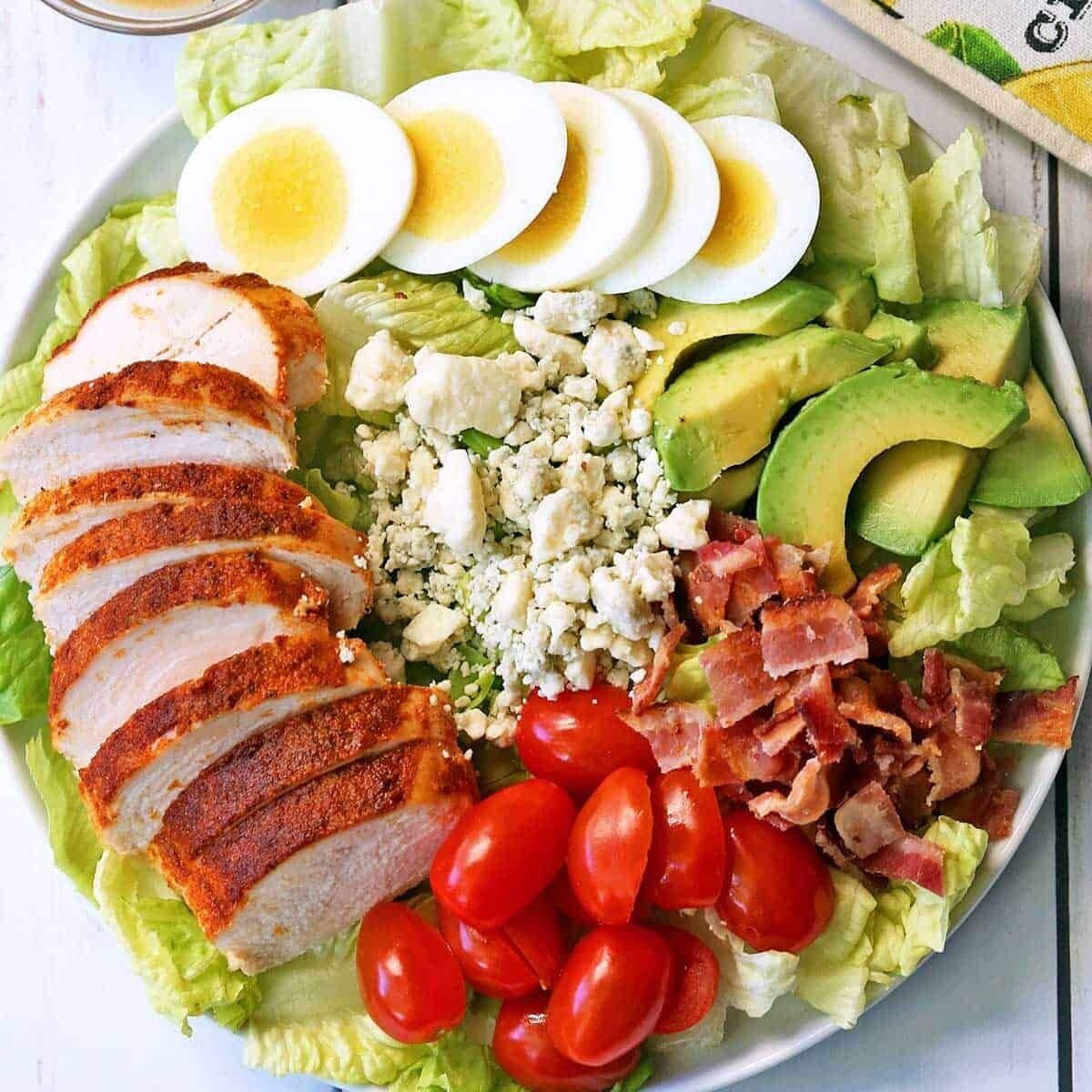 En sallad med olika ingredienser, bland annat salladsblad, avokado, tomater och hårdkokta ägg.
