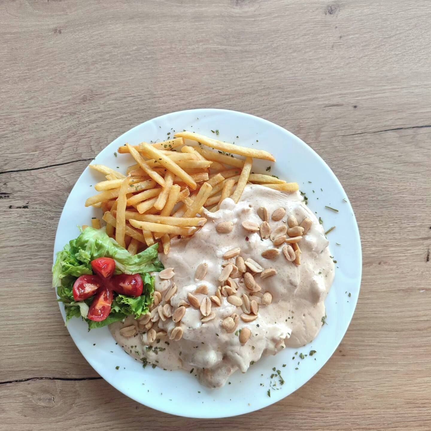 A plate with a meat dish, French fries, and a side salad.