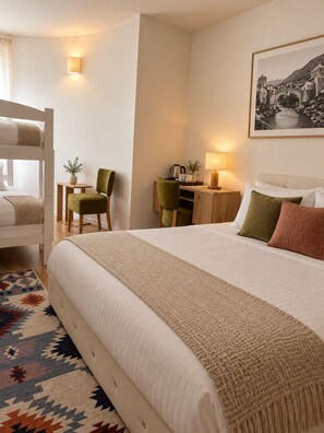 Une chambre d’hôtel avec un lit, un bureau, une chaise et un lit superposé.