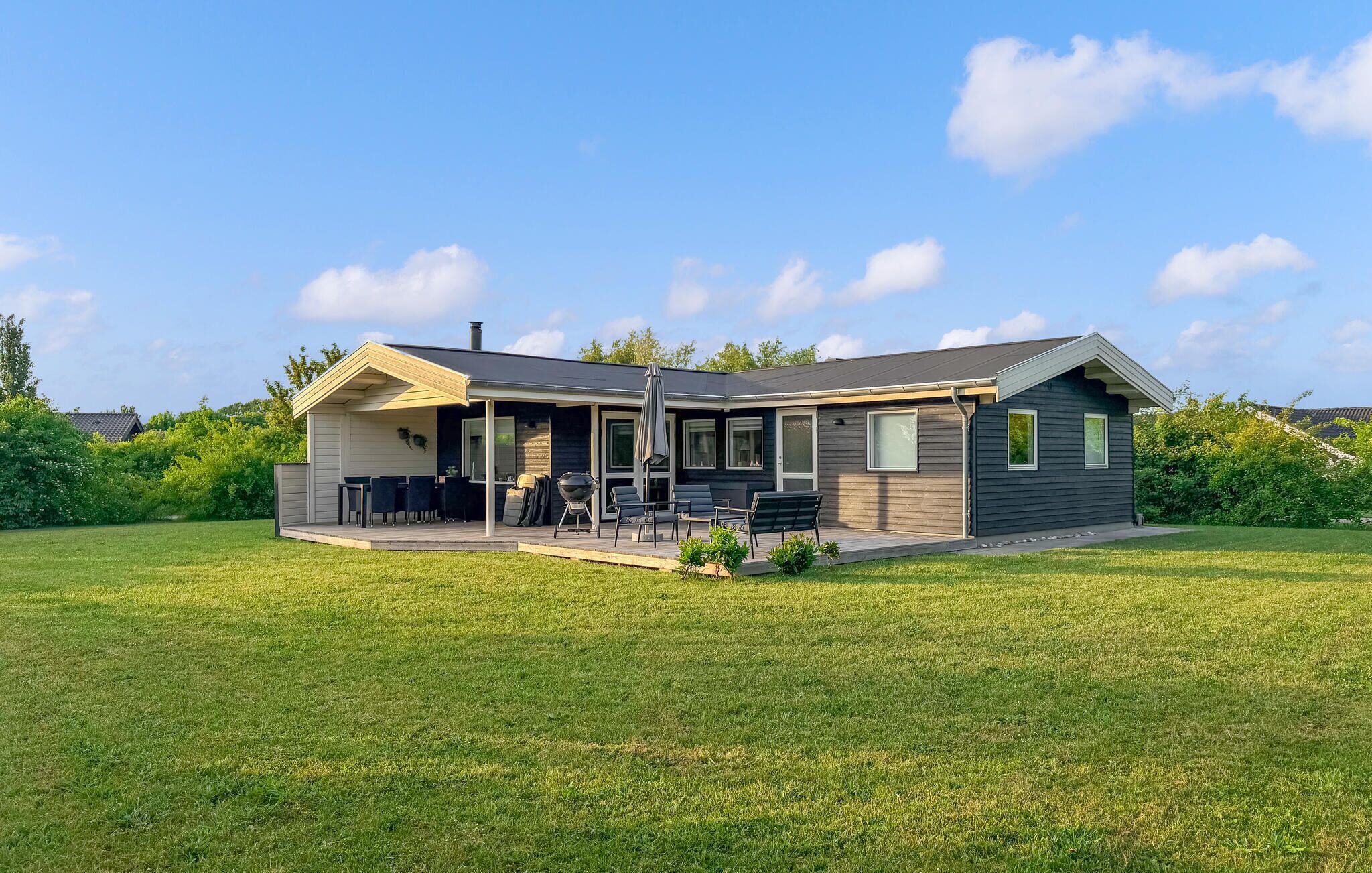 Une maison moderne de plain-pied dotée d’un patio couvert, d’un barbecue et d’une pelouse bien entretenue.