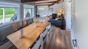 Una cucina moderna con un tavolo di legno, sedie bianche e un divano grigio.